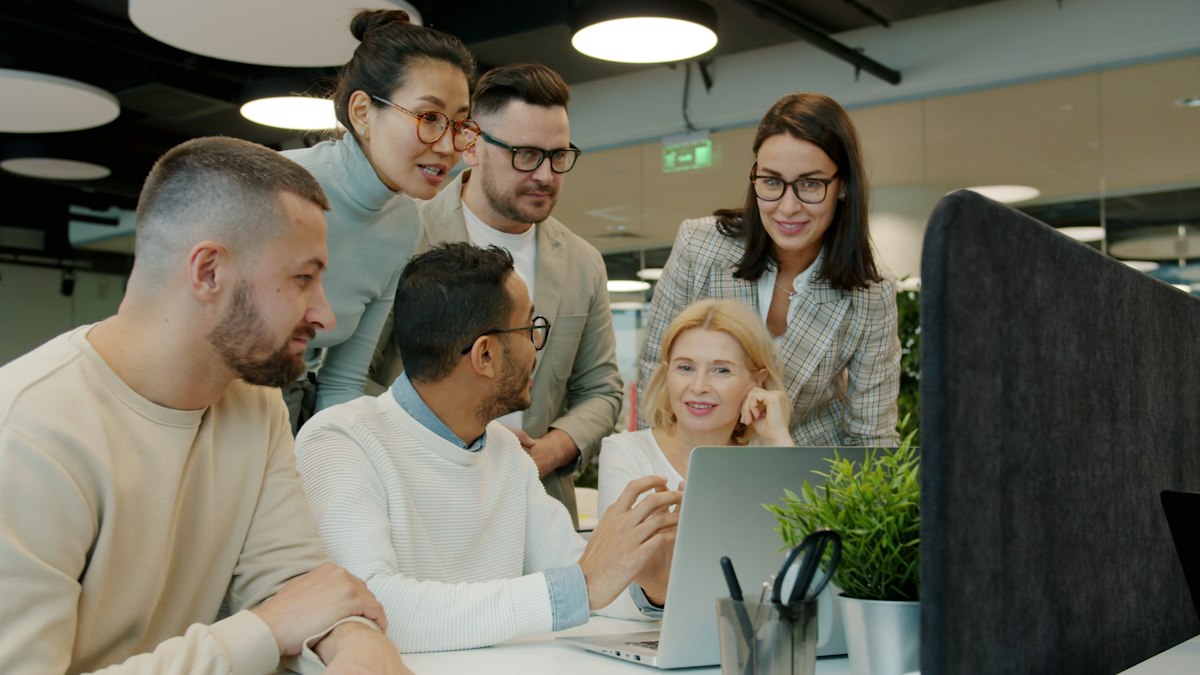 A team collaborating around a laptop while planning a SaaS product budget