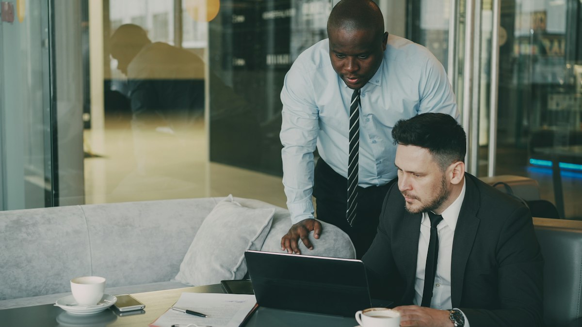 Two professionals collaborating over a laptop during a software engineer hiring discussion